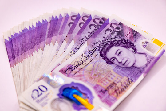 A stack of twenty pound banknotes from the Bank of England featuring Queen Elizabeth II, isolated on white background