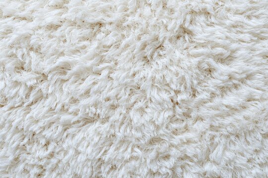 High angle close-up view of a soft, fluffy, textured, white rug or carpet surface