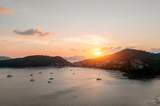 A glorious sunset drenches the serene bay of Kata Beach Thailand in warm orange and pink light