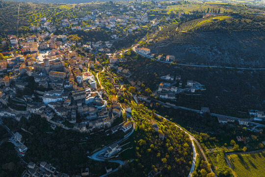 Aerial view of the historic hilltop town of Capestrano featuring the Castello Piccolomini surrounded by stone houses and lush green valleys during golden hour in Capestrano, Abruzzo, Italy.
