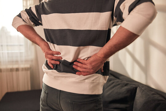 Man with hip, back, spine and sciatica pain at home.