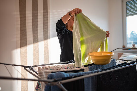 Woman drying laundry on a rack at home.