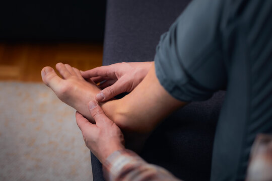 Man at home holding painful injured foot.