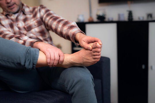 Man at home holding painful injured foot.