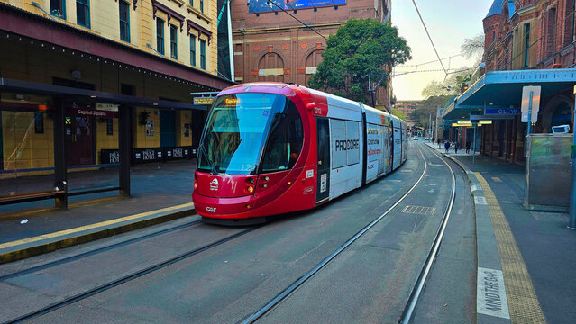 tram in sidney.public transport of australia.Tram travels along the tracks in an urban area while people wait nearby for their rides in a busy city at day