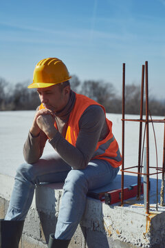 Construction worker having a heatstroke on a hot sunny day, headache, issues on a construction site outdoors.