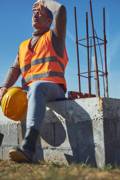 Construction worker having a heatstroke on a hot sunny day, headache, issues on a construction site outdoors.