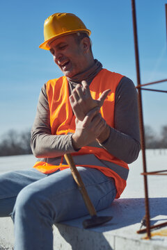 Construction worker having a accident and injured wrist on a construction site outdoors.