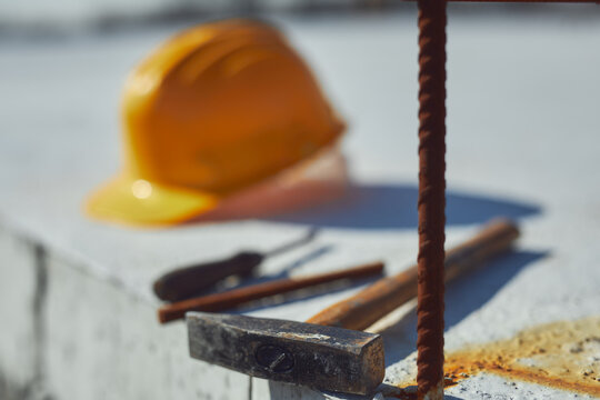 Construction tools and helmet on a cement foundation with iron rebar.