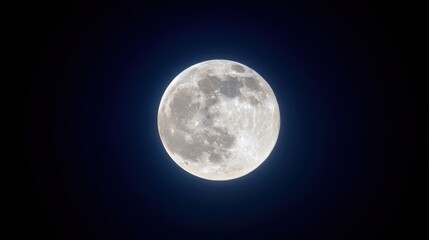 Obraz premium A full moon with craters and seas glows softly against a deep blue to black night sky.