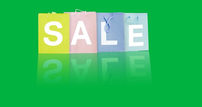 Digital animation of sale text over multiple colorful shopping bags against black background