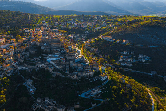 Aerial view of the historic Castello Piccolomini and the stone buildings of the hillside town nestled in the green valleys of Capestrano, Abruzzo, Italy.