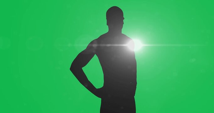 Silhouette of male swimmer against spot of light on black background