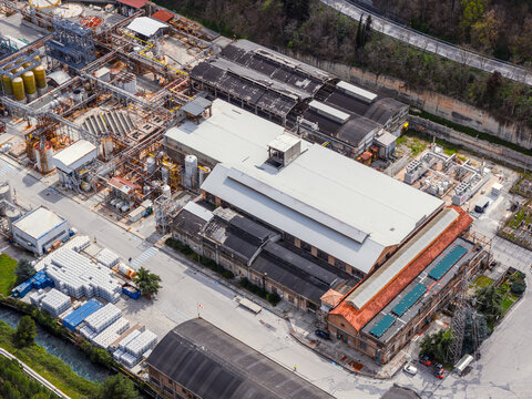 Aerial view of an industrial complex with large warehouses, storage tanks, and intricate piping systems in Bussi sul Tirino, Abruzzo, Italy.