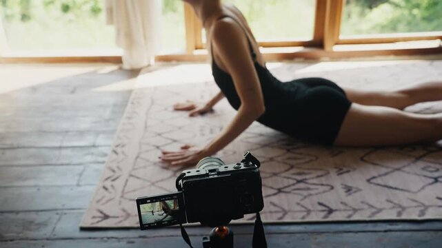 Woman vlogging yoga practice performing cobra pose