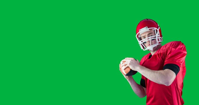 Caucasian male rugby player wearing a helmet catching a rugby ball against black background