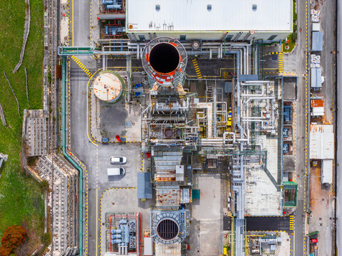 Aerial view of industrial infrastructure with complex piping, storage tanks, and a large chimney stack in Bussi sul Tirino, Abruzzo, Italy.