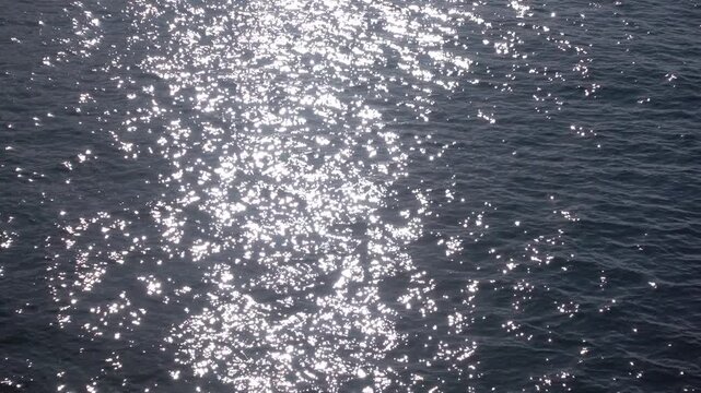 High contrast dark sea water motion texture, breezy wind surface pattern with sun glitter 