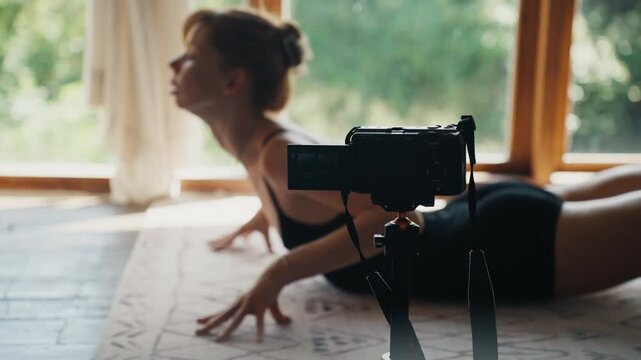 Yoga instructor vlogging cobra pose at home
