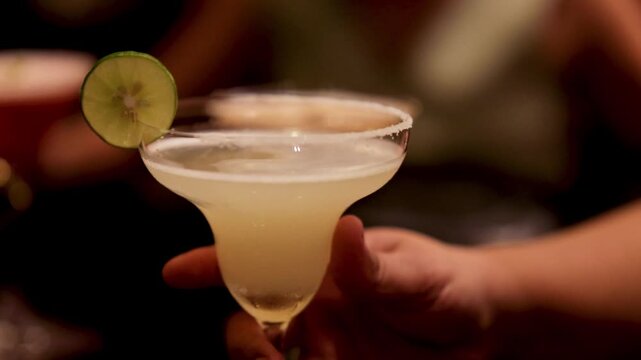 Close up of a refreshing margarita cocktail with lime and salt rim served at a party.