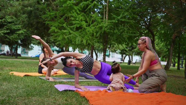 Women practicing side stretch yoga pose on mats during group outdoor session in green park. Side stretch, yoga, mats, group, park.