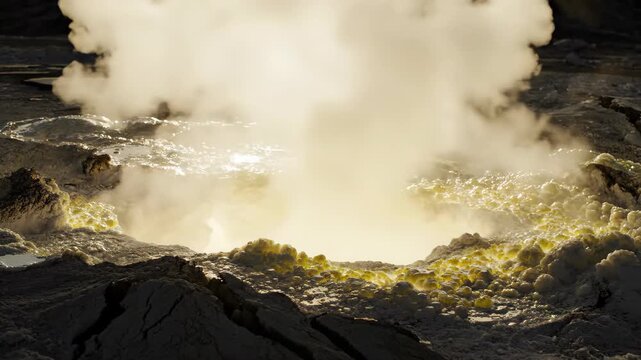 Macro shot of volcanic hydrothermal vent with sulfur deposits erupting steam under intense golden backlighting