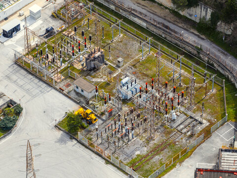 Aerial view of an electrical substation with transformers, high-voltage insulators, and a yellow maintenance vehicle in Bussi sul Tirino, Abruzzo, Italy.