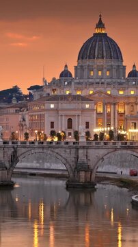 Breathtaking view of St Peter's Basilica and St Angelo Bridge in Rome at sunset. Evening city lights reflect beautifully in the calm waters of the Tiber River
