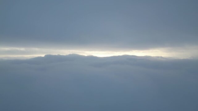 Aerial View Above Thick Clouds with Sun Peeking Through Horizon
