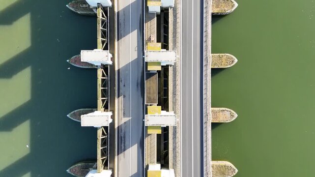 Top down aerial shot over the lock complex with cars on the road and repeating concrete forms below.