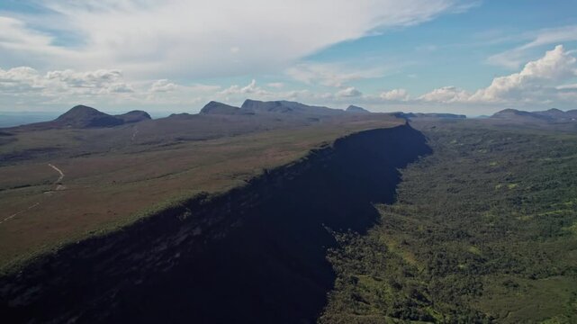 Aerial view of a vast plateau and forest under a clear sky with clouds