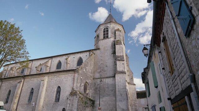 The bell tower of Saint-F&eacute;licien church rises above the medieval houses of the village of Issigeac. Architectural heritage of Perigord. Lateral slow motion tracking shot.