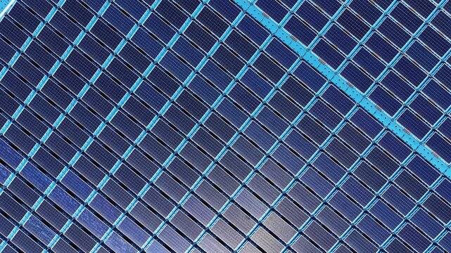 Close-up overhead view of a floating solar farm showing rows of photovoltaic panels with blue aluminum framing, monocrystalline cells, and modular pontoon mounting structure