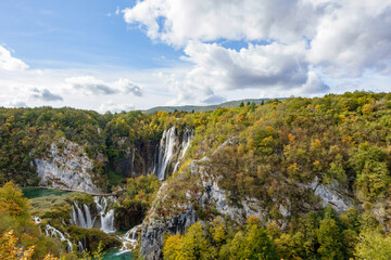 Naklejka premium Panoramic autumn view of Veliki Slap waterfall in Plitvice Lakes National Park, Croatia, scenic canyon landscape with turquoise water and colorful forest under a cloudy sky