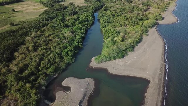 river delta along the narrow, white sandy beach of a rural town.  Drone, aerial
