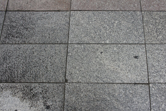 Concrete pavers close up background. Texture of gray and brown square paving tile. Pattern of sidewalk tiles in the street.	