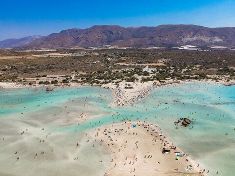 Mesmerizing drone view of Elafonisi Beach, highlighting its unique pink-hued sands and shallow turquoise waters along the coast of Crete. A breathtaking aerial capture of one of Greece&rsquo;s most iconic
