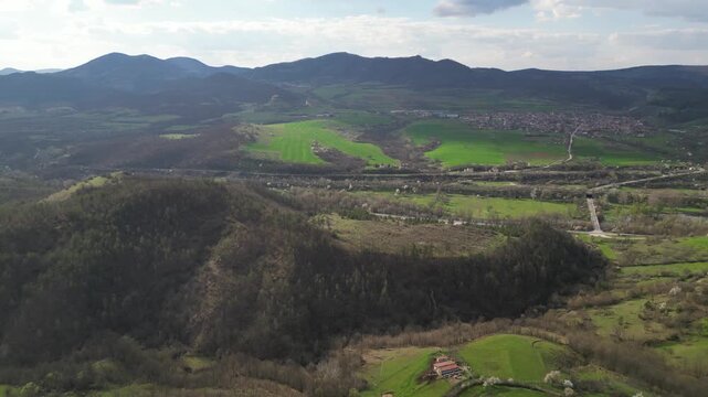Aerial panoramic view of green hills and rural village in mountain valley