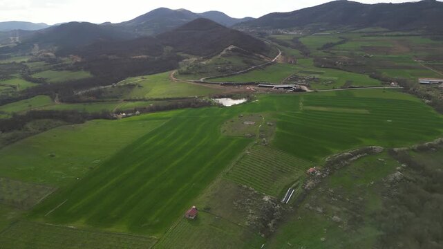 Aerial panoramic view of green hills and rural village in mountain valley