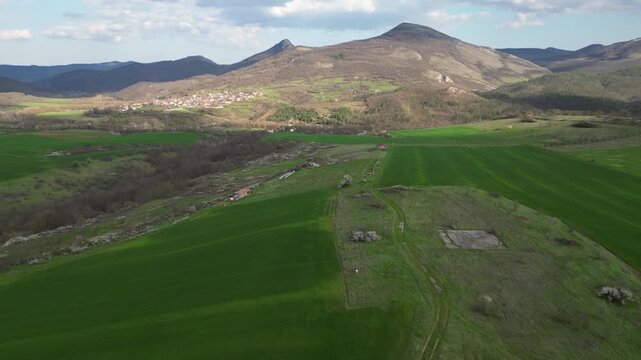 Aerial panoramic view of green hills and rural village in mountain valley