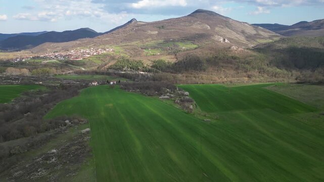 Aerial panoramic view of green hills and rural village in mountain valley
