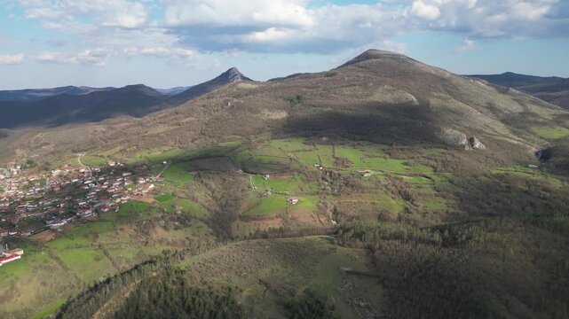 Aerial panoramic view of green hills and rural village in mountain valley