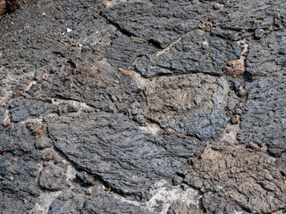Fototapeta premium Detailed texture of solidified volcanic lava flow showing rough surface patterns and geological formations on Lanzarote