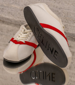 White lace-up sneakers with red stripes and a Celine logo label on the upper. Milan - Italy, 28 March 2026