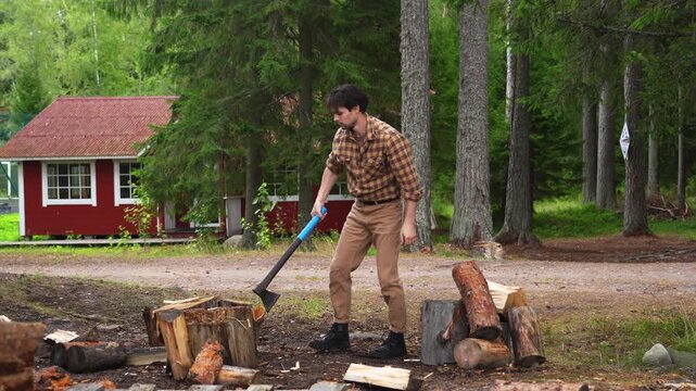 Cinematic 4K ProRes 422 slow motion of a man chopping wood in front of a red cottage. Authentic rural life and lumberjack style.