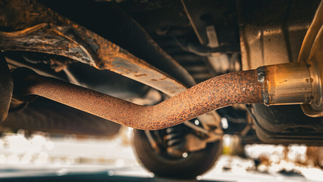a rusty exhaust pipe located underneath a vehicle. automotive background. abstract banner or design element.