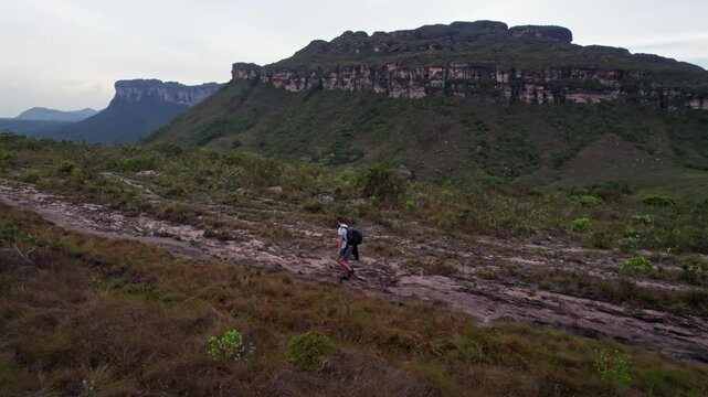 Hiker Walk on Rocky Terrain Towards Distant Mountains in Vally