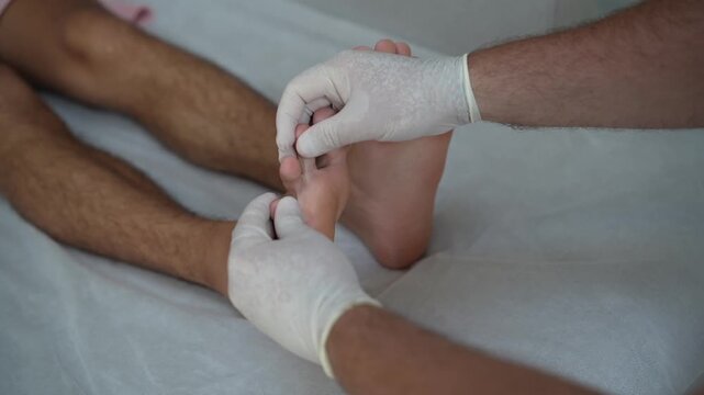 Doctor performing foot examination on male patient. Close-up video of podiatry check, testing mobility and sensitivity during clinical assessment in medical setting.