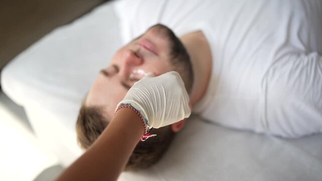 Cosmetologist applying eye patches on both eyes of male patient. Close-up video of skincare procedure for hydration, anti-aging and under-eye treatment in clinic.