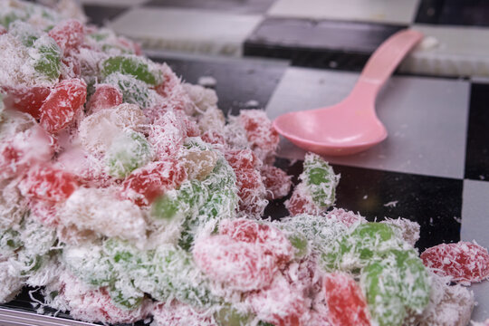 Close-up of Cenil, a colorful traditional Indonesian steamed cassava cake with grated coconut. Delicious Cenil snack served with fresh grated coconut on a checkerboard surface. A popular authentic Ind